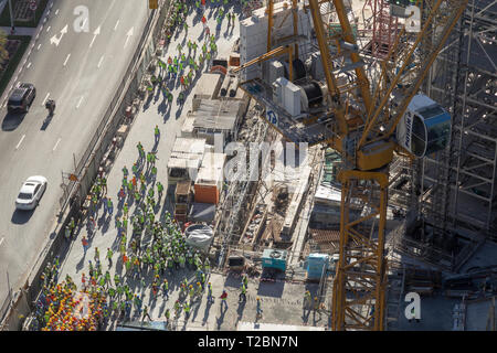 Arial vista di un grande gruppo di lavoratori edili, raggruppati sul lato della strada durante un drill incendio Foto Stock