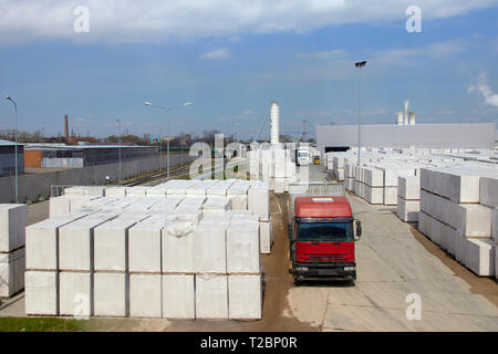 Vista della fabbrica di produzione di vegetali autoclavato calcestruzzo aerato. Molti pacchetti di blocchi su pallet mettere uno sull'altro in un magazzino esterno. Carrello ri Foto Stock