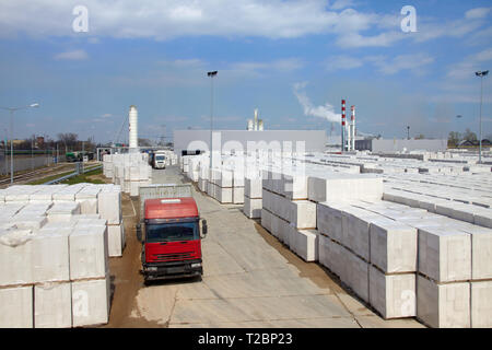 Vista della fabbrica di produzione di vegetali autoclavato calcestruzzo aerato. Molti pacchetti di blocchi su pallet mettere uno sull'altro in un magazzino esterno. Carrello ri Foto Stock