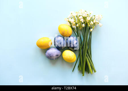 Layout di pasqua con uova colorate e un mazzo di fiori di bucaneve. Festa laica piana. Foto Stock