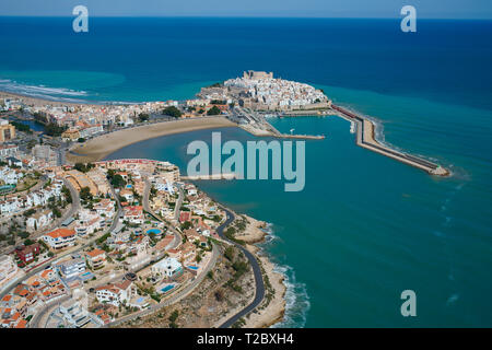 VISTA AEREA. Residenze turistiche che si affacciano sulla città storica su una penisola sulla costa mediterranea. Peñíscola, Comunità Valenciana, Spagna. Foto Stock