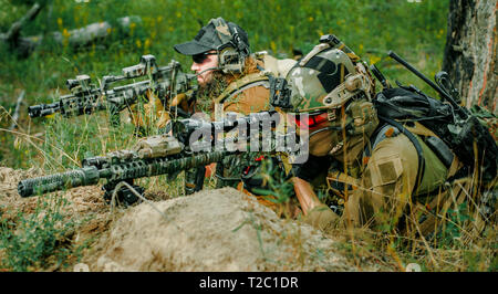 Soffice come l'aria sniper uomini con le pistole giacciono sulla collina. Sniper e aimer sul funzionamento della foresta Foto Stock