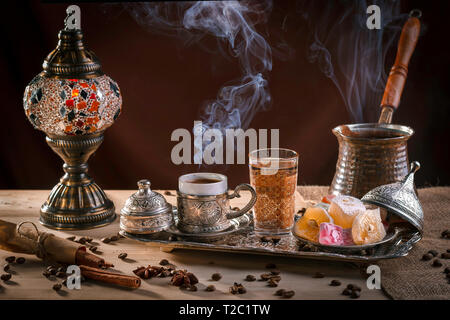 Caffè alla Turca in un cezve e le tradizionali delizie Turche. Vapore oltre una tazza. Lampada di antiquariato Foto Stock