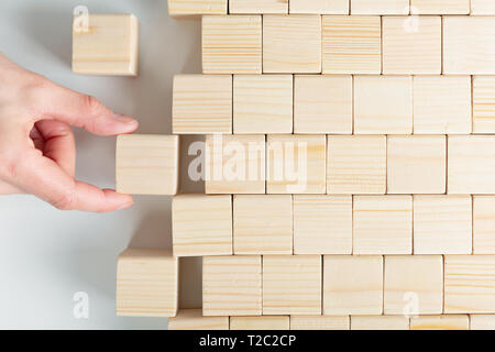 Donna con le mani in mano di finitura cubo di legno pattern. Collocazione pezzo mancante Foto Stock