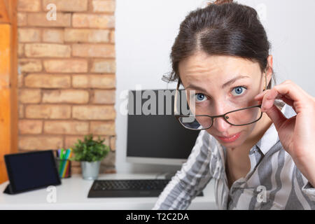Ufficio donna in bicchieri con sorpresa di fronte l'espressione in home office Foto Stock