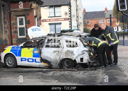 I vigili del fuoco di occuparsi di due auto della polizia che erano stati distrutti dopo essere stata impostata su fuoco fuori Goldthorpe stazione di polizia nel South Yorkshire in un sospetto incendio doloso. Foto Stock