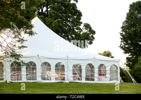Un matrimonio bianco tenda istituito in un prato circondato da alberi e con i lati verso il basso Foto Stock