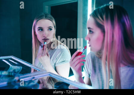 No alla droga. Ritratto di giovane donna bella applicando le sue labbra con il rossetto rosso in prossimità di linee di cocaina nei night club di servizi igienici. Lei si guarda allo specchio Foto Stock