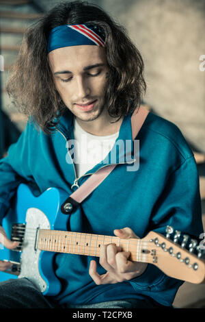 Con i capelli lunghi esperto musicista con stoppie nero a cantare e suonare allo stesso tempo Foto Stock