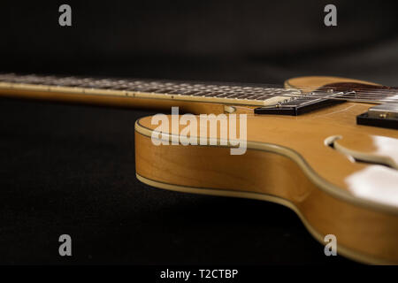 Vintage archtop chitarra in acero naturale close-up alto angolo vista laterale nella messa a fuoco selettiva su sfondo nero Foto Stock