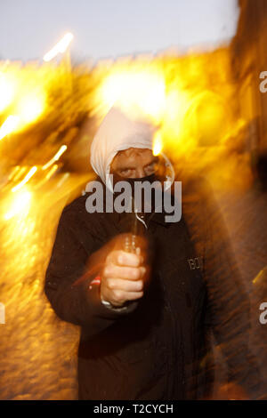 Il crimine di coltello. Uomo incappucciato brandendo un coltello butterfly Foto Stock