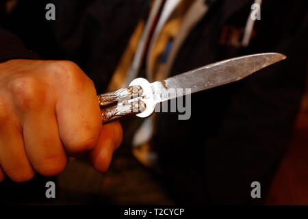 Il crimine di coltello. Uomo incappucciato brandendo un coltello butterfly Foto Stock