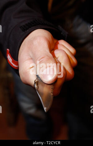 Il crimine di coltello. Uomo incappucciato brandendo un coltello butterfly Foto Stock