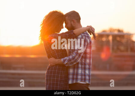 Amato giovane abbracciando e toccando la loro fronte al tramonto, Vista laterale Foto Stock
