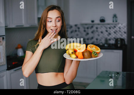 Sport ragazza in una cucina con verdure Foto Stock