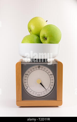 Vintage in legno bilance da cucina isolato su sfondo bianco con mela verde Foto Stock