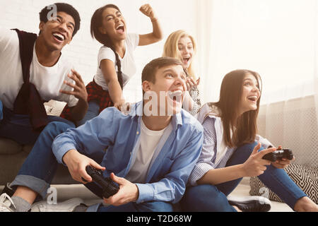 Emozionato amici per giocare con i videogiochi a casa e divertirsi Foto Stock