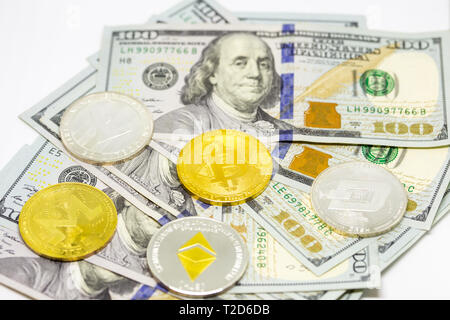 Cryptocurrency bitcoin, dash, litecoin, ethereum, monerocoins visualizzata su un mucchio di banconote da cento dollari. Foto Stock