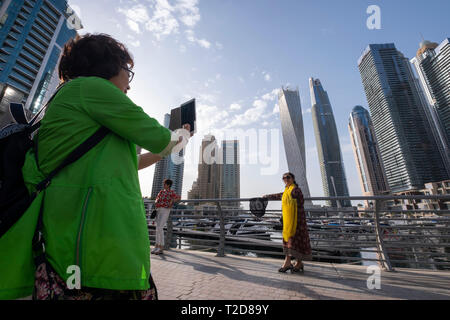 Turisti asiatici in posa per fotografie a Dubai Marina, Dubai, Emirati Arabi Uniti Foto Stock