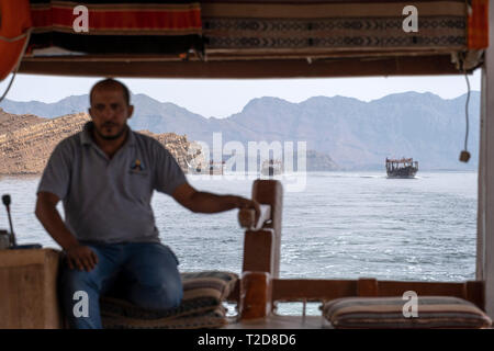 Cruise tour a bordo di un decorata tradizionalmente con Sambuco Arabo barca di legno lungo le montagne rocciose della penisola di Musandam in Oman Fiordi Foto Stock