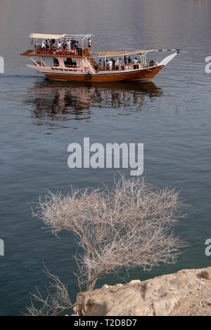 Decorata in maniera tradizionale dhow Arabo di legno di crociera in barca lungo le montagne rocciose della penisola di Musandam in Oman Fiordi Foto Stock