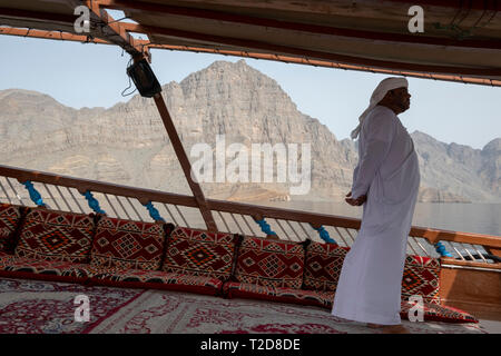 Cruise tour a bordo di un decorata tradizionalmente con Sambuco Arabo barca di legno lungo le montagne rocciose della penisola di Musandam in Oman Fiordi Foto Stock