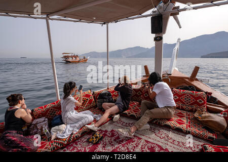 Cruise tour a bordo di un decorata tradizionalmente con Sambuco Arabo barca di legno lungo le montagne rocciose della penisola di Musandam in Oman Fiordi Foto Stock