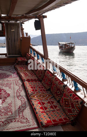 Cruise tour a bordo di un decorata tradizionalmente con Sambuco Arabo barca di legno lungo le montagne rocciose della penisola di Musandam in Oman Fiordi Foto Stock