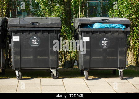 Cassonetti per il riciclaggio, nero cassonetti per i rifiuti residui in piedi sul marciapiede Foto Stock