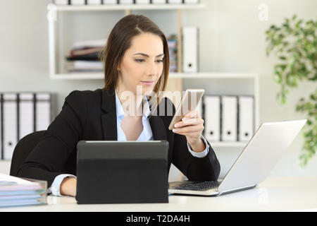 Occupato imprenditrice utilizzando dispositivi multipli di un telefono portatile e tablet in ufficio Foto Stock