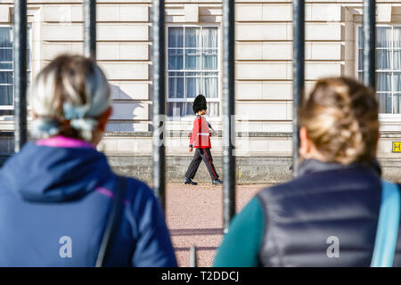 London, Regno Unito - 3 Ottobre 2018 - vista posteriore di due turisti a guardare una sentinella del granatiere guardie di pattuglia fuori Buckingham Palace Foto Stock
