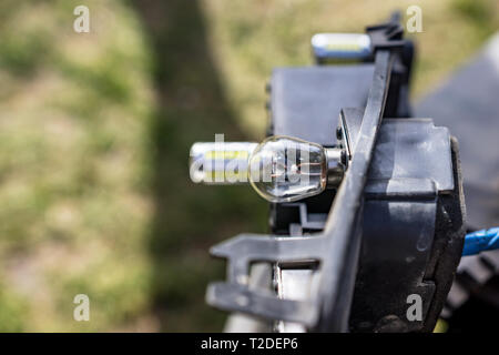 Un close-up di un open-headed faro del veicolo. Messa a fuoco selettiva in sfuoca i l uomo con la sua mano sulla scatola polverosa. Foto Stock