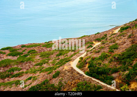 Guardando verso il basso sulla strada di montagna con il blu oceano sottostante. La curvatura della strada intorno montagne. Foto Stock