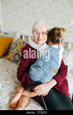 Momenti felici con grande nonna, senior lady trascorrere del tempo di qualità con la sua pronipote. Felice abbraccio Foto Stock