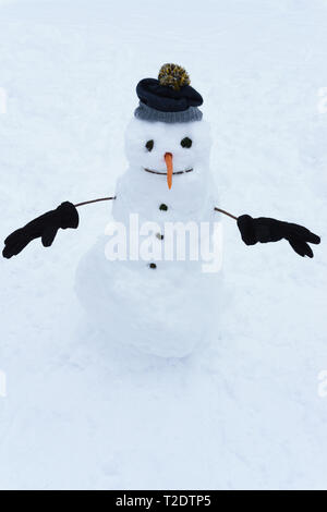 Pupazzo di neve in guanti e cappello con arancia naso. Il Natale e l'inverno. Foto Stock