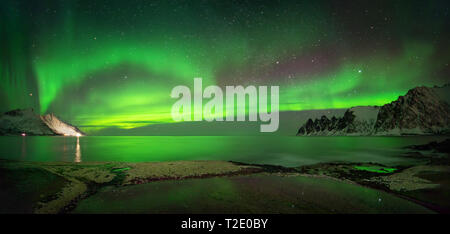 Panorama di aurora su Tugeneset costa rocciosa con le montagne sullo sfondo, Senja, Norvegia Foto Stock