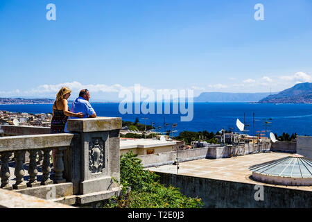 Messina, Sicilia, Italia. Un romantico l uomo e la donna di guardare al di sopra del porto di Messina e al resto d'Italia. Foto Stock