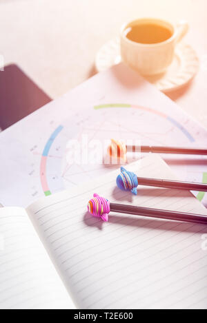 Aprire il notebook per la scrittura di idee e di nascita astrologico Natal grafico posa su uno sfondo grigio. Il caffè e il pianeta le penne nelle vicinanze. Vista dall'alto. Idea di Astrol Foto Stock