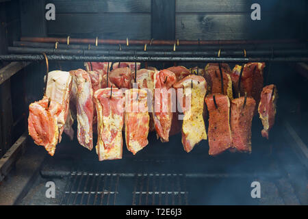 Il cibo tradizionale di prosciutto affumicato, pancetta di maiale in una carne appesi in affumicatoio nazionali sulle stringhe Foto Stock