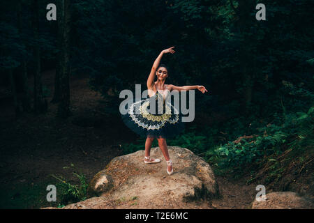 Ballerina in posa nella foresta, bilanciamento sulla roccia. Foto Stock