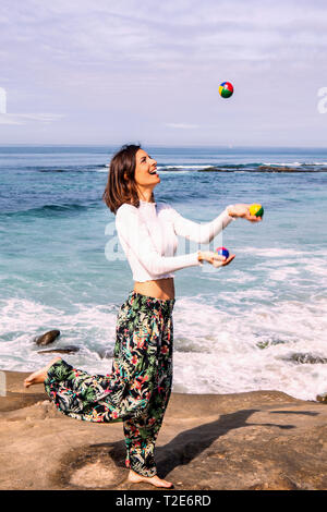 Giovane donna la giocoleria in riva al mare Foto Stock