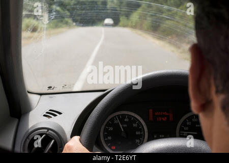 Irriconoscibile la persona alla guida della vettura, la vista della strada attraverso il parabrezza Foto Stock