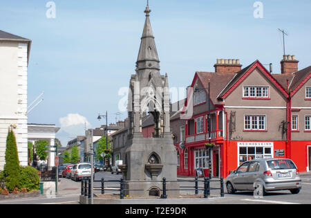 Auto e traffico oltre ornata fontana pubblica irlandese potabile nella storica città di Lismore County Waterford, Irlanda in un caldo sole in tarda primavera. Foto Stock