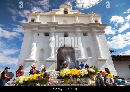 La gente locale brucia incenso e vende fiori gialli di fronte a Iglesia De Santo Tomas in un giorno di mercato a Chichicastenango, Guatemala Village Foto Stock