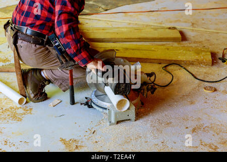 Lavoratore con sega elettrica il taglio di un tubo in PVC per la costruzione di una nuova costruzione commerciale Foto Stock