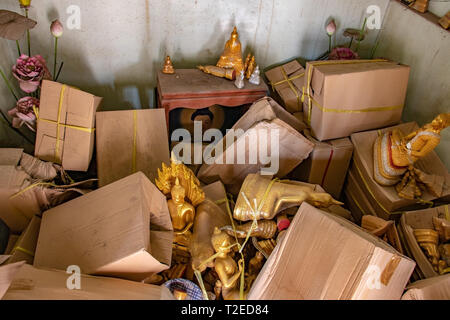 La stanza di deposito con il disordine di una pila di scatole peper e oggetti sacri inclusa la statue di Buddha nel tempio buddista, Thailandia. Foto Stock