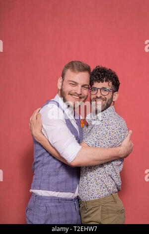 Due uomini, sorridente coppia gay, cercando di fotocamera, abbracciando l'altra. Foto Stock