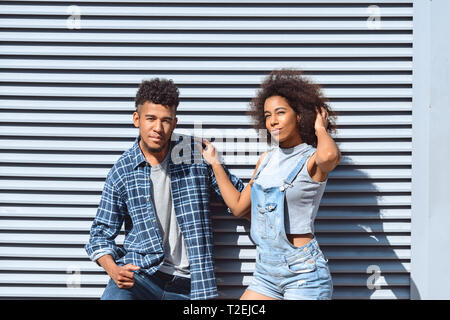 Giovane ragazzo e ragazza isolato permanente sulla parete avvolgente in posa per fotocamera a sorridere fiducioso Foto Stock