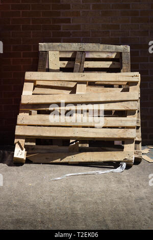 Grandi rotte pallet in legno appoggiata contro un muro di mattoni Foto Stock