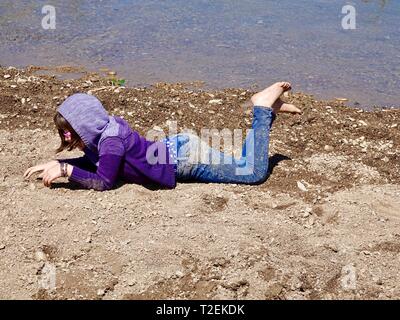 Carino ragazza di 10 anni, in viola maglione e vestiti sporchi, giocando sulle rive del Fiume Ventura, Ojai, CALIFORNIA, STATI UNITI D'AMERICA Foto Stock